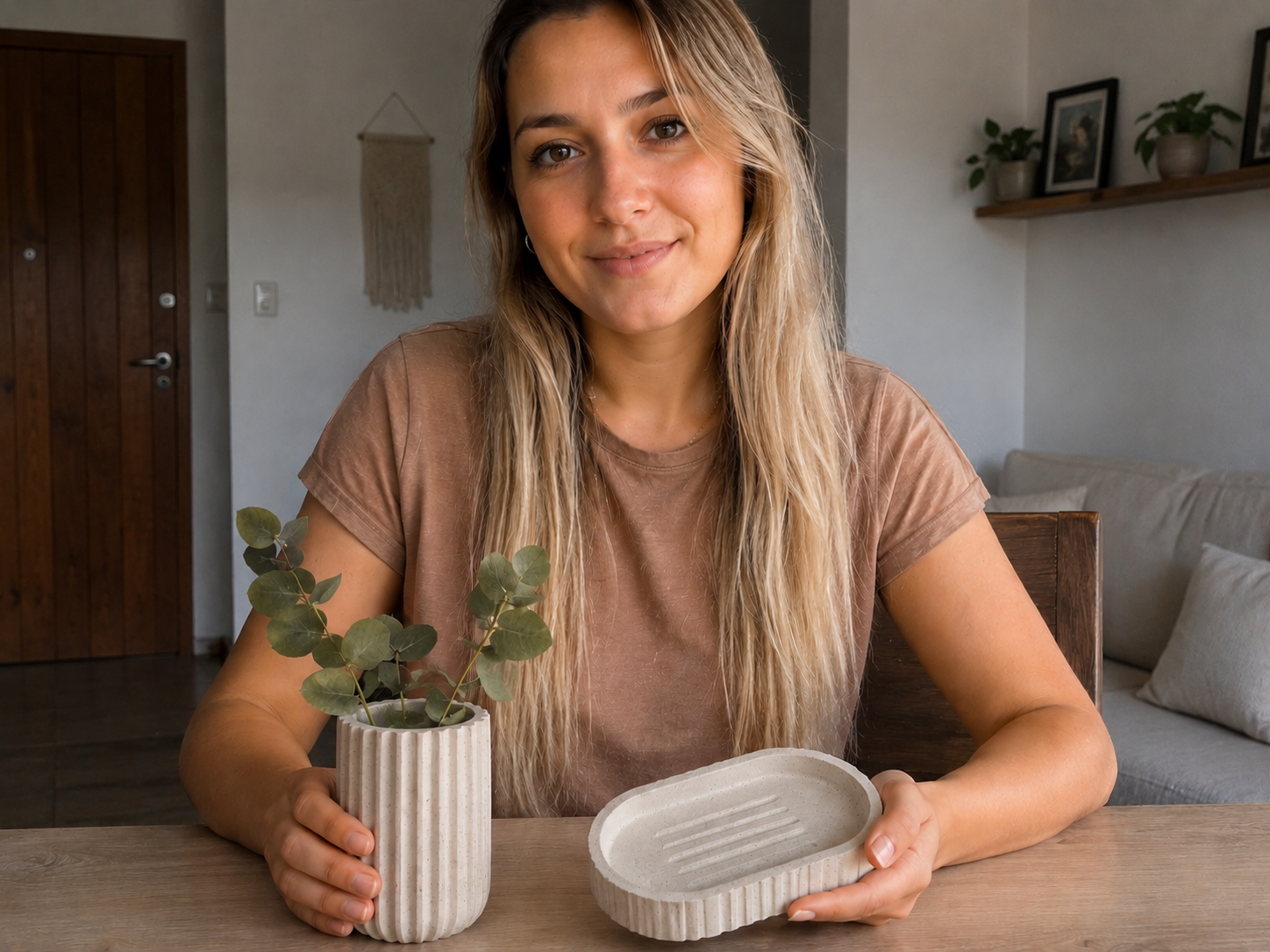 Mujer trabajando en una mesa de taller rodeada de piezas de cemento decorativo terminadas